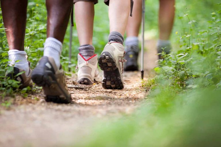 Close-up of hiking boots of a group of hikers on dirt trail