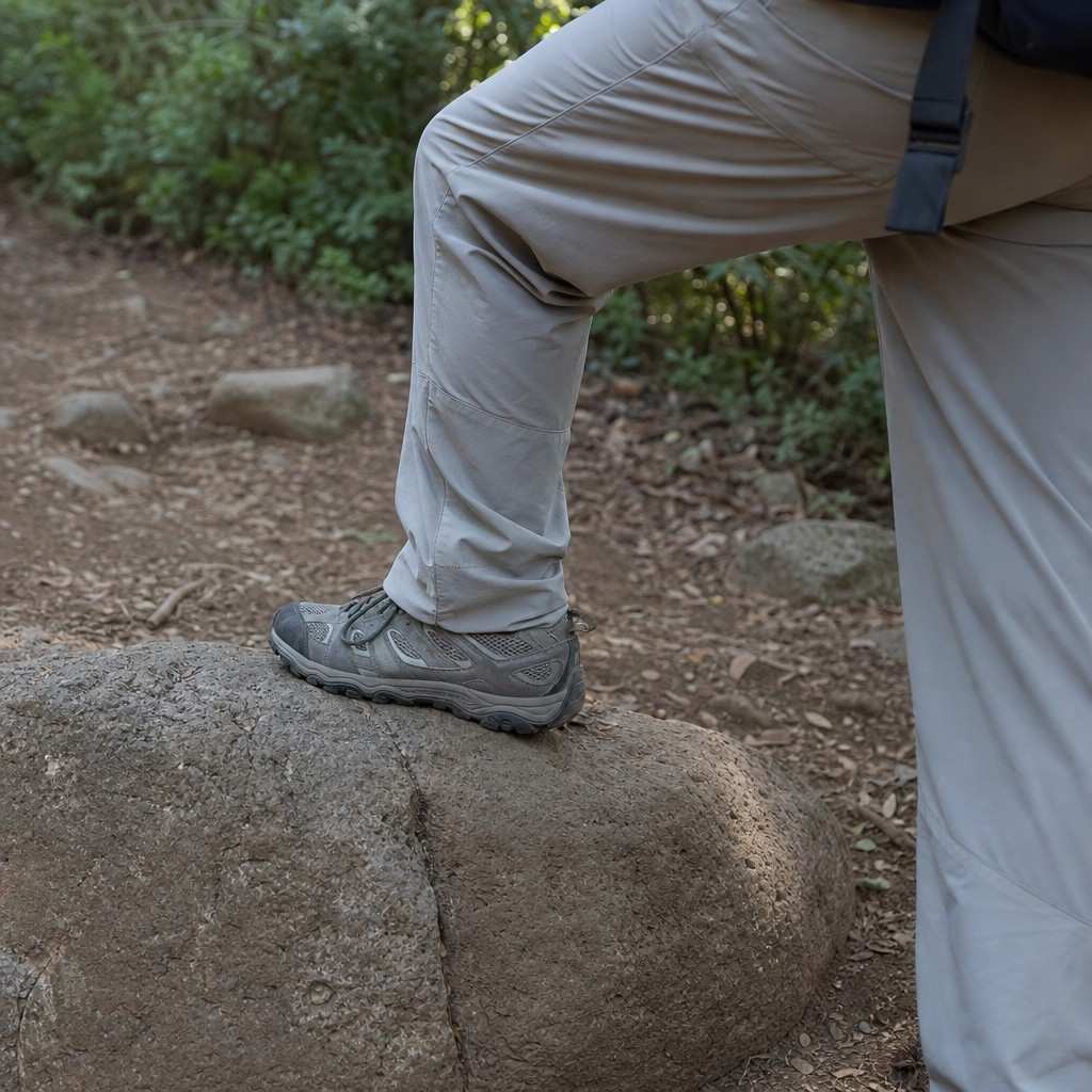 A hiker's trail pants stretching as they step up onto a low rock