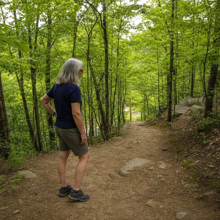 An older hiker pausing mid-descent to rest on an easy switchback