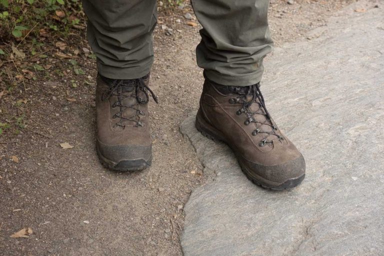 Hiking boots planted on a mixed surface of gravel and embedded rock