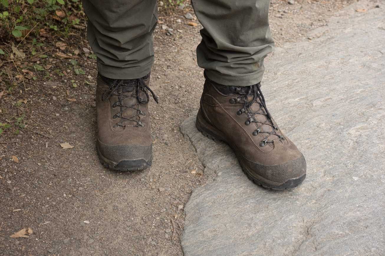 Hiking boots planted on a mixed surface of gravel and embedded rock