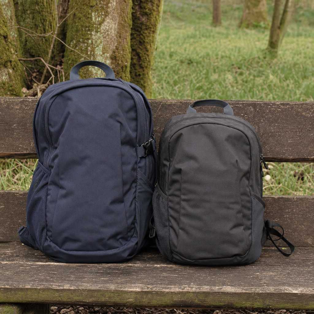 Two small daypacks of slightly different sizes side by side on a wooden bench